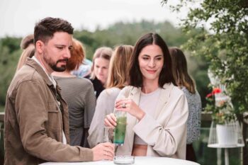 P&auml;rchen steht mit Drinks am Stehtisch
