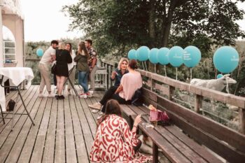 Terrasse mit t&uuml;rkisen Ballons und Personen im Gespr&auml;ch