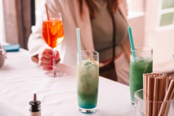 Frau steht bei der Bar und h&auml;lt ihr Getr&auml;nk