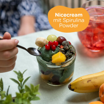 Hand mit L&ouml;ffelt n&auml;hert sich der Spirulina Nicecream in einer Sch&uuml;ssel