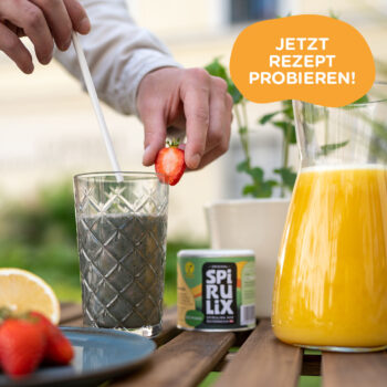 Glas mit gr&uuml;nem Spirulix Smoothie neben Krug mit Orangensaft