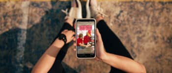 Person sitzt am Boden und h&auml;lt Smartphone in der Hand