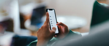 Person mit gr&uuml;nem Pulli h&auml;lt Smartphone