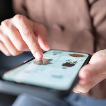 Eine Person navigiert auf ihrem Smartphone durch eine Online-Shopping-Oberfl&auml;che mit Fokus auf Passwortsicherheit und interagiert mit dem Zeigefinger. Das Bild zeigt Hand und Ger&auml;t vor einem leicht unscharfen Hintergrund.