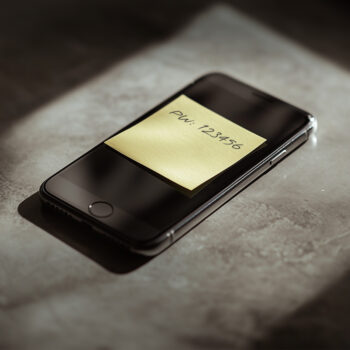 Dunkles Smartphone mit gelbem Post-it auf dem